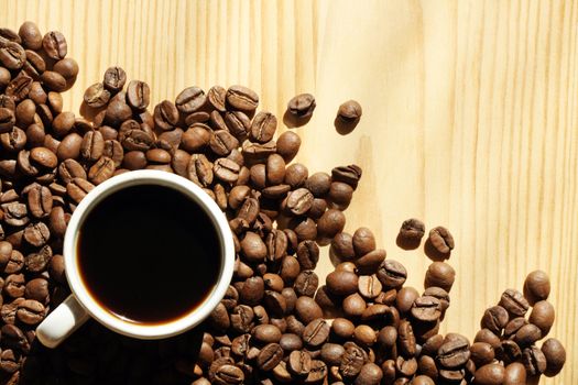 Cup of black coffee and coffee beans on wooden background