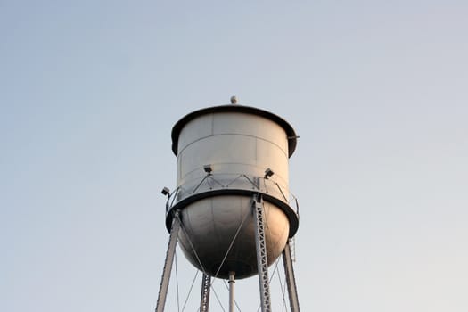 An old silver water tower lost in the blue sky