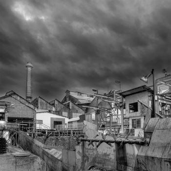 Old abandoned factory with dramatic clouds in sky.