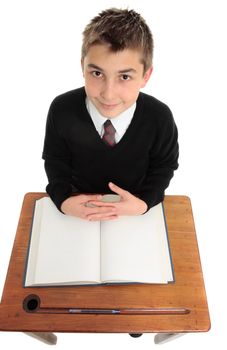 A young male school student in uniform looking up from desk.  Above view.