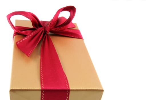 A Christmas present wrapped in gold paper with red ribbon.
