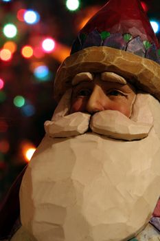 A santa claus figurine with Christmas lights in the background.
