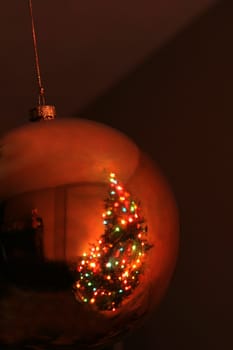 A reflection of a Christmas tree in a gold bauble ornament.