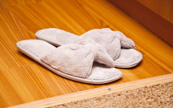 white plush slippers on hardwood floor. Concept - comfort and relaxation 