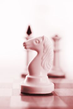 Knight on chess board ready to play, red toned
