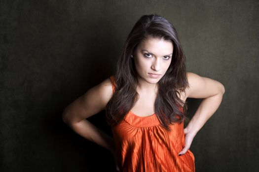Frustrated Hispanic woman in orange on green background