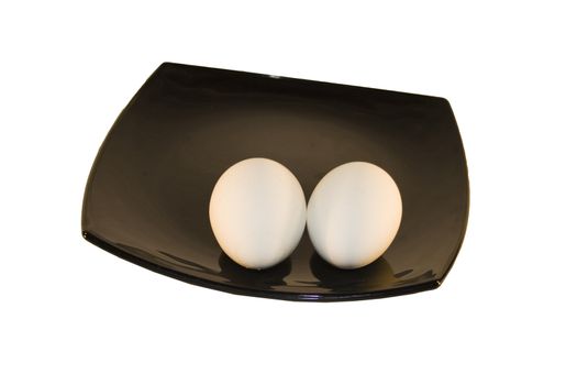 Black glass square plate with 2 eggs isolated over white