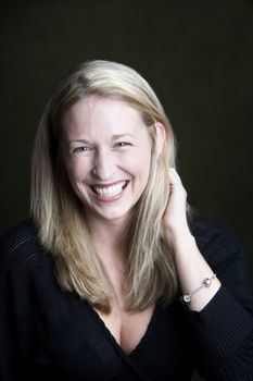 Portrait of pretty blonde laughing woman on a dark background