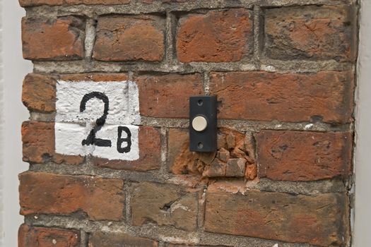 Housenumber sign painted on brick wall