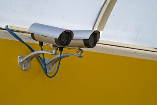 Security camera mounted on a yelow wall