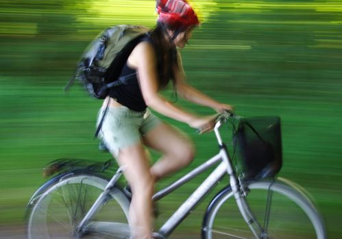 Woman biking in forest in motion.