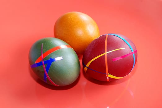 three colored ester eggs isolated over red