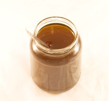 A honey jar with a spoon, on a white background