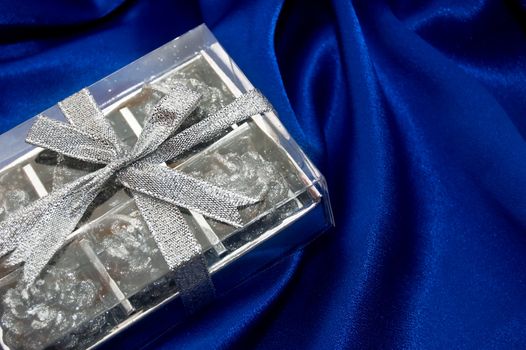 silver gift box on blue satin fabric