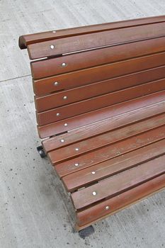 Corner of a wood bench against a concrete background