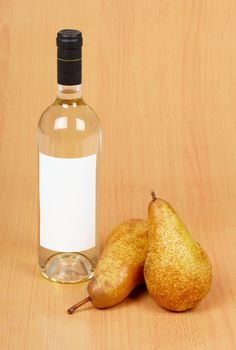 Bottle of white wine and ripe pears on wood