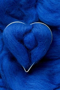 The blue wool heart lies on blue background