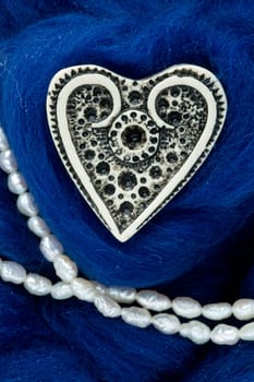 The white ivory heart lies on the blue wool