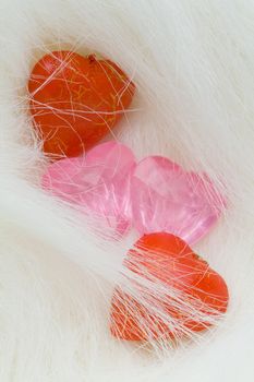 Two red wood hearts and two pink crystal hearts lie on the fur