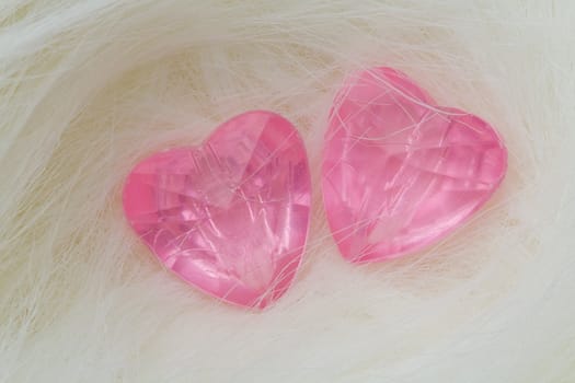 Two pink crystal hearts lie on the fur