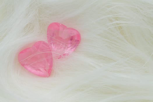 Two pink crystal hearts lie on the fur