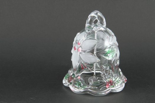 A holiday bell made of glass on a grey background.