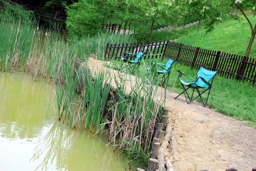 Folding blue chairs by muddy yellowish pond