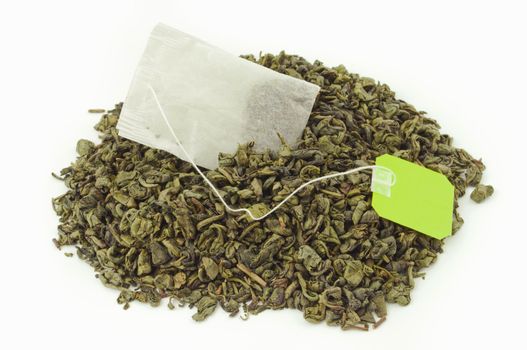 Tea bag inside a mount of dried green tea leaves