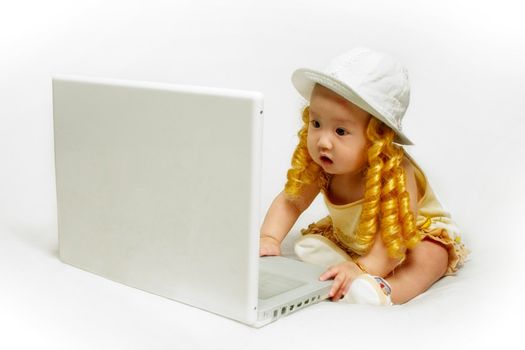 A baby girl is looking at a laptop