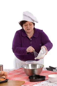 Happy chef standing at the table adding some flour