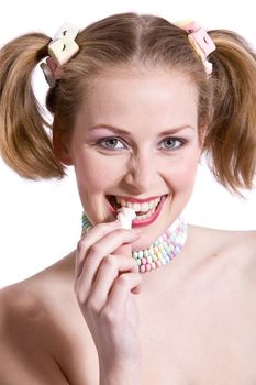Cute blond girl with ponytails biting in a candy
