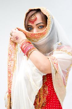 Elegant Bengali bride with veil in front of mouth, isolated