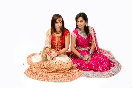 Two beautiful harem girls or belly dancers or Hindu brides sitting, isolated
