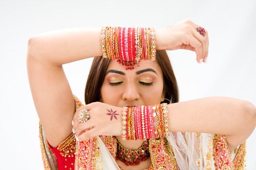 Beautiful face of a Bengali bride with her arms across her head covered with colorful bracelets and eyes closed, isolated