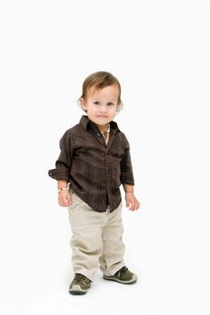 A cute toddler boy dressed in brown standing, isolated