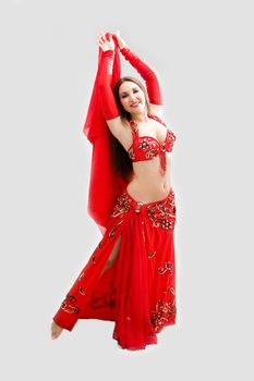 Beautiful belly dancer in red outfit with arms up, isolated