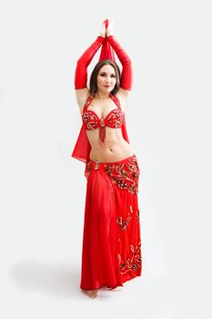 Beautiful belly dancer in red outfit with arms up, isolated