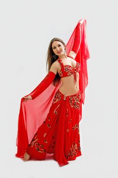 Beautiful belly dancer in red outfit holding veil, isolated