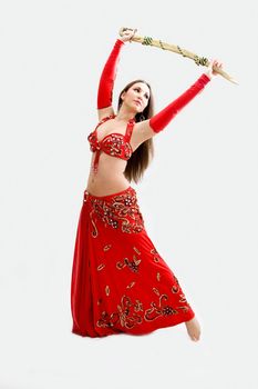 Beautiful belly dancer in red outfit holding sword, isolated