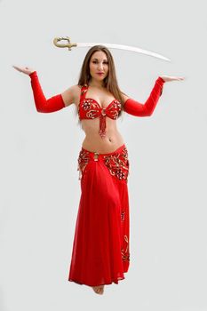 Beautiful belly dancer in red outfit with sword on her head, isolated