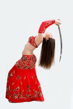 Beautiful belly dancer in red outfit holding sword hanging backward, isolated