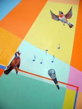 Painted on the colored wall birds which singing a song