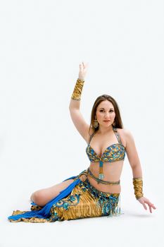 Beautiful belly dancer in blue outfit laying on floor, isolated