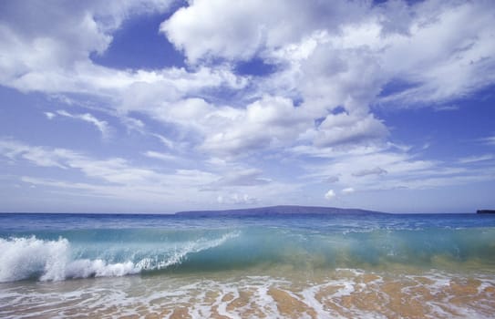 Ocean wave rolling onto beach under a dramatic sky