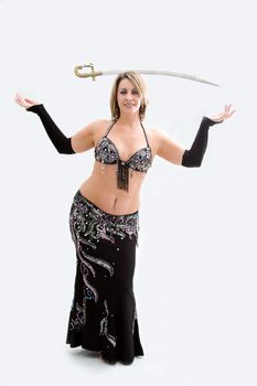 Beautiful belly dancer in black outfit balancing sword, isolated