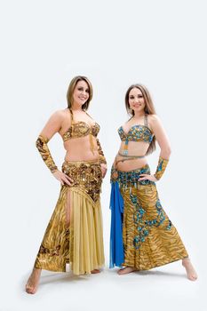 Two beautiful belly dancers dressed in gold and blue, isolated