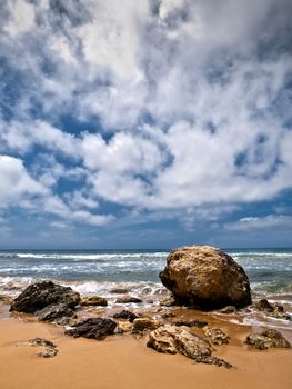 A lone boulder surrounded bu other fragments of rock on the edge of the coastline