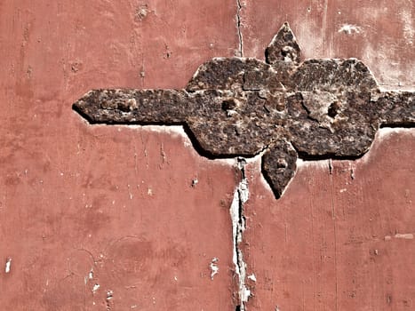 Detail image of an old rusty hinge on a red door