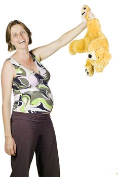 Funny portrait of pregnant woman laughing and holding a teddy by its leg.Isolated over white.