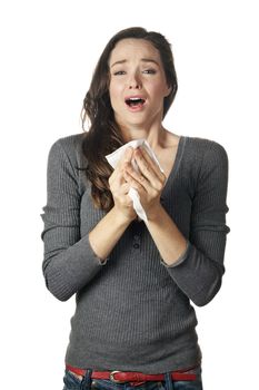 An attractive woman with hay fever or a cold sneezing into tissue